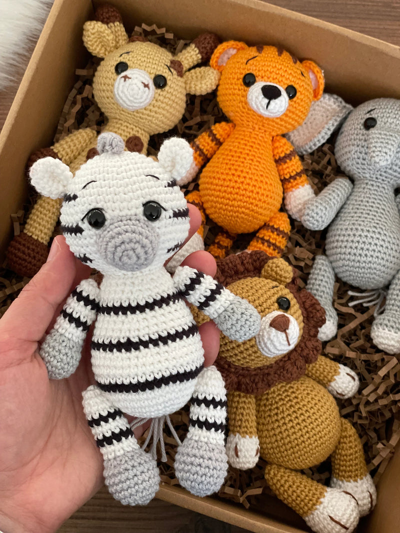 Handmade Safari Animals set including giraffe, tiger, elephant, zebra, and lion, all made with 100% cotton yarn, perfect for unique toddler gifts and imaginative play. All of them lying inside a gift box.