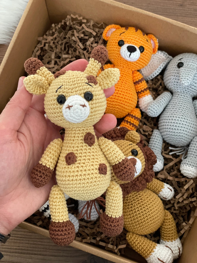 Handmade Safari Animals set including giraffe, tiger, elephant, zebra, and lion, all made with 100% cotton yarn, perfect for unique toddler gifts and imaginative play. All of them lying inside a gift box.