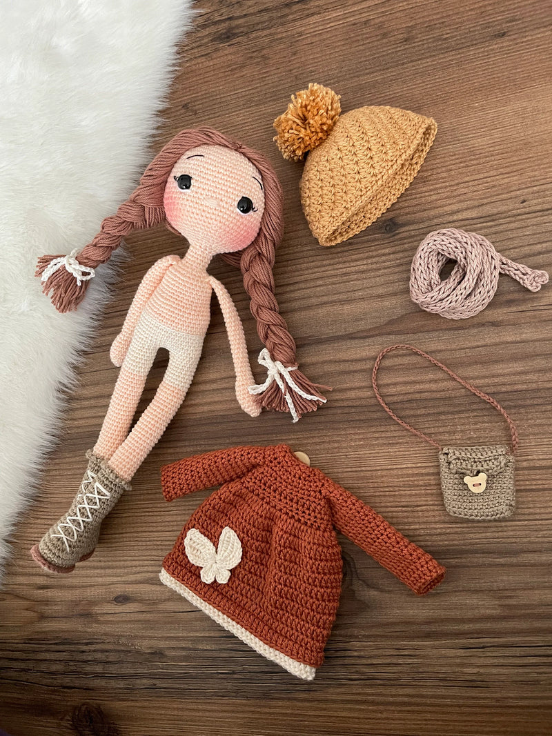 Handmade crochet winter girl doll in a brick-colored dress and hat, crafted with 100% cotton yarns. This amigurumi doll is customizable with a name on a leather label, making it a perfect, personalized gift for children and nursery decor.