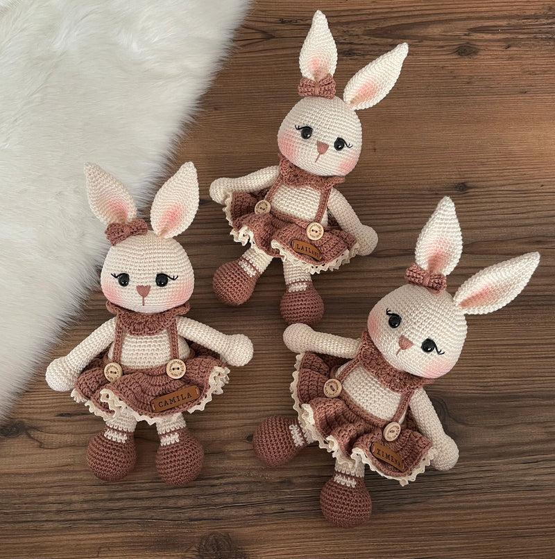 Three Handmade crocheted Chubby Girl Bunny Rabbit Toy with a cute dress and bow, customizable with a name on a leather label. Perfect for children and nursery decor.