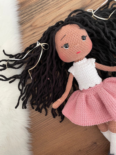 Handmade crocheted Pink Skirted Afro-American Doll with long brown hair, a cute skirt, customizable with a name on a leather label. Ideal for nursery decor and as a personalized gift.