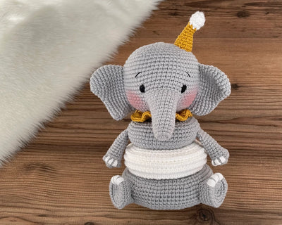 Handmade crocheted elephant educational toy with stackable rings, designed for Montessori learning. Features soft grey yarn, a yellow hat, and customizable name option.