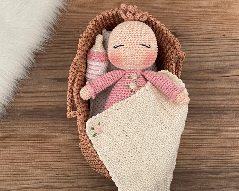 Handmade crochet Baby Girl in a Basket set, featuring an amigurumi baby doll with a pink outfit, wrapped in a soft blanket, and personalized with a name on a leather label, perfect for unique baby gifts and imaginative play.