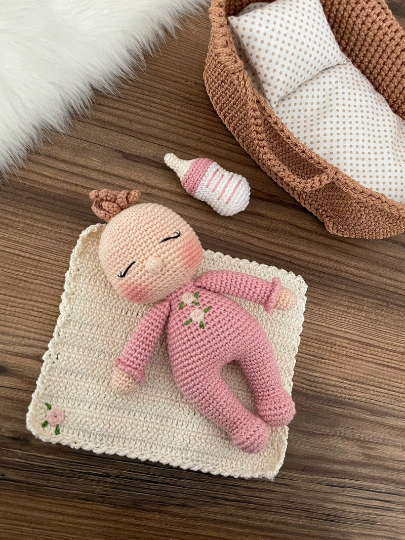 Handmade crochet Baby Girl in a Basket set, featuring an amigurumi baby doll with a pink outfit, wrapped in a soft blanket, and personalized with a name on a leather label.