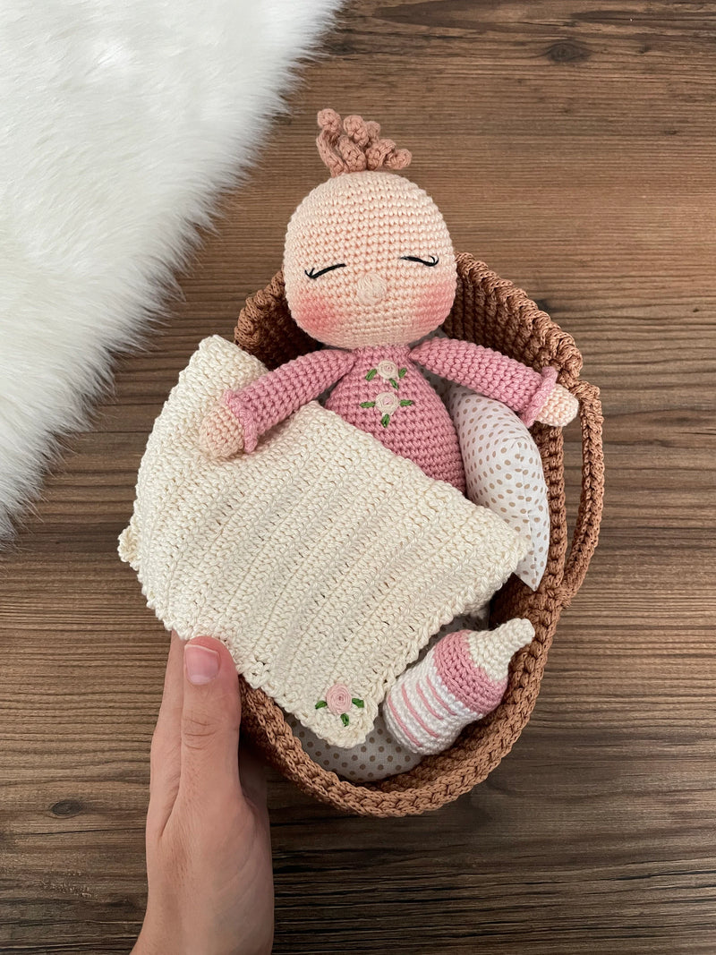 Handmade crochet Baby Girl in a Basket set, featuring an amigurumi baby doll with a pink outfit, wrapped in a soft blanket, and personalized with a name on a leather label.