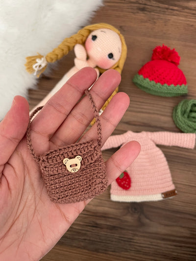 Handmade crocheted Strawberry Girl Doll featuring a pink dress, strawberry detail, and a cute braided hairstyle. Customizable with a name on a leather label, made using amigurumi techniques. Perfect as a personalized gift or nursery decor.