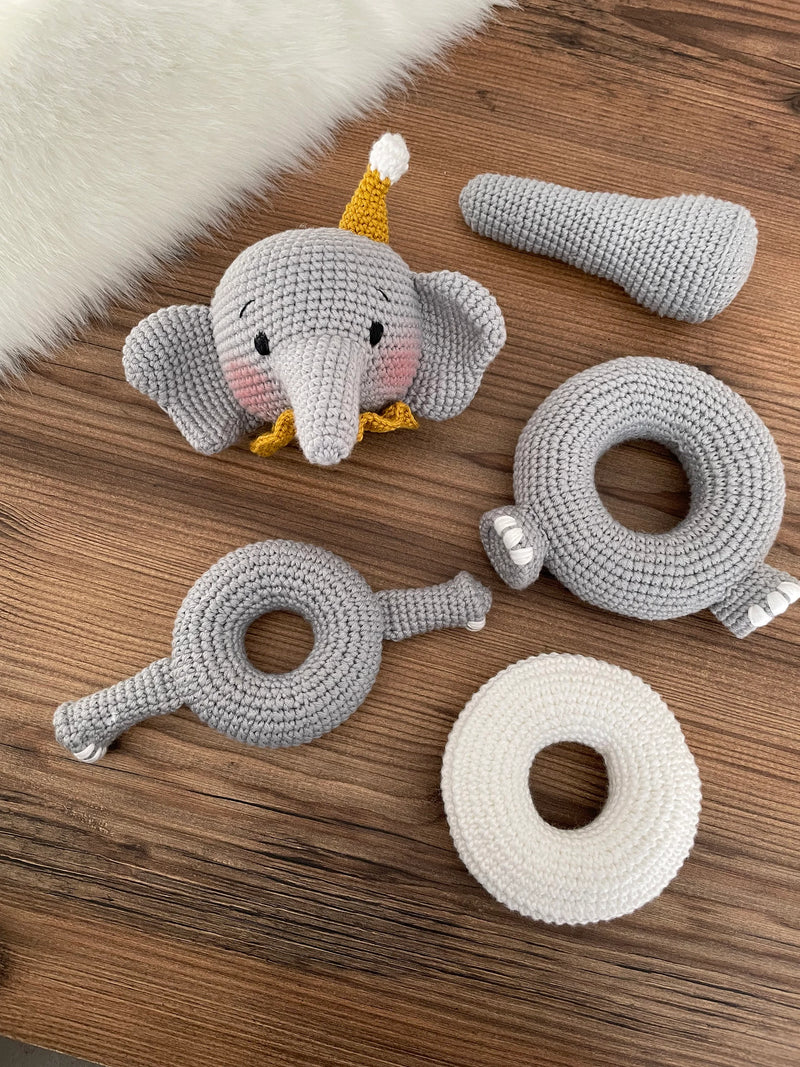 Handmade crocheted elephant educational toy with stackable rings, designed for Montessori learning. Features soft grey yarn, a yellow hat, and customizable name option.