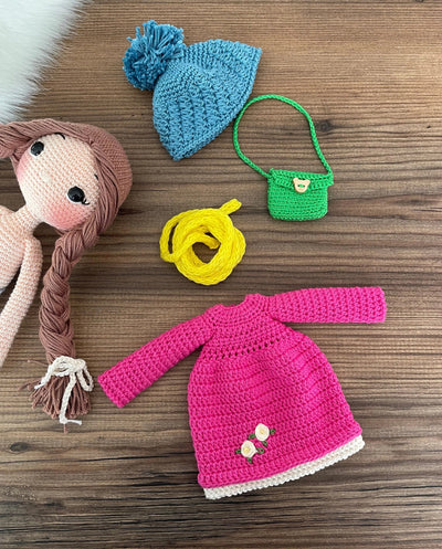 Handmade crocheted Magenta Winter Girl Doll featuring a magenta dress, flower detail, and a cute braided hairstyle. Customizable with a name on a leather label, made using amigurumi techniques. Perfect as a personalized gift or nursery decor.