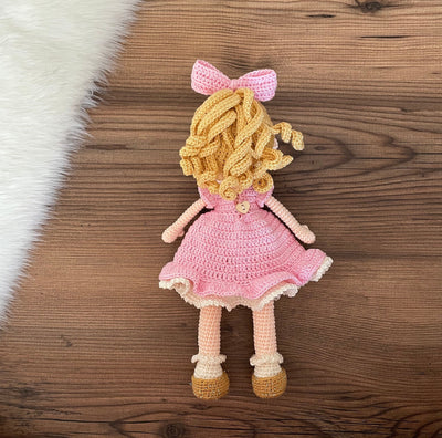 Handmade Pink Nina Doll with blonde hair, wearing a pink dress with a strawberry detail, made with 100% cotton yarn, customizable with a name on a leather label.