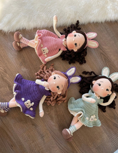 Handmade Bunny Girl Dolls with bunny ears, wearing a pink, purple and mint green dresses with bunny details, made with 100% cotton yarn, customizable with a name on a leather label.