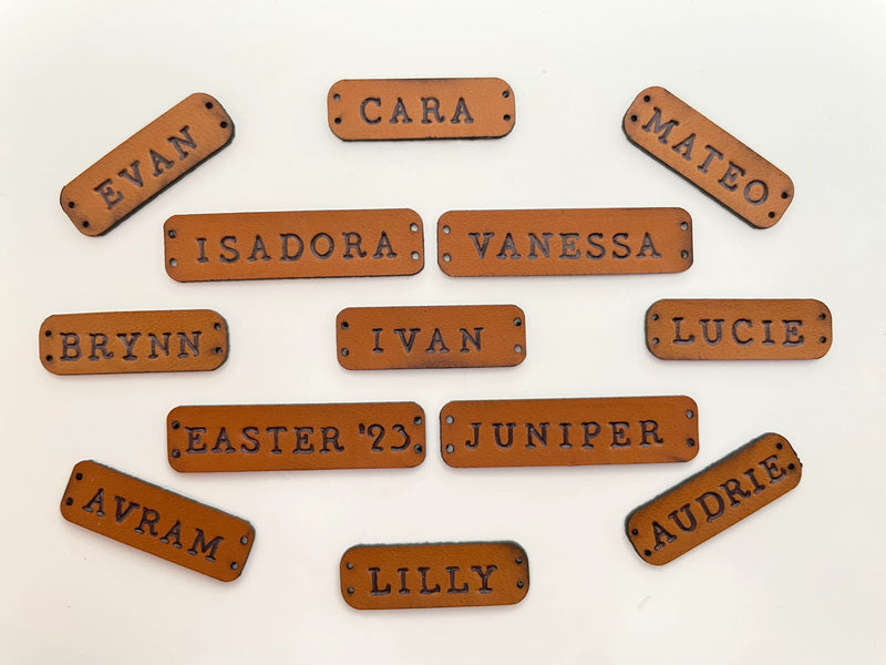 Custom leather name tags with various names displayed on a light background