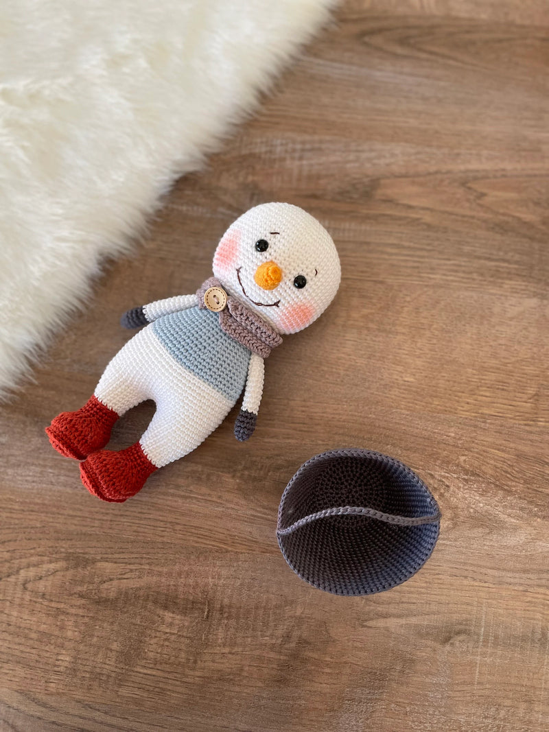 Handmade crocheted snowman toy with red boots, customizable with a name on a leather label, made using amigurumi techniques, perfect as a holiday gift or decor.