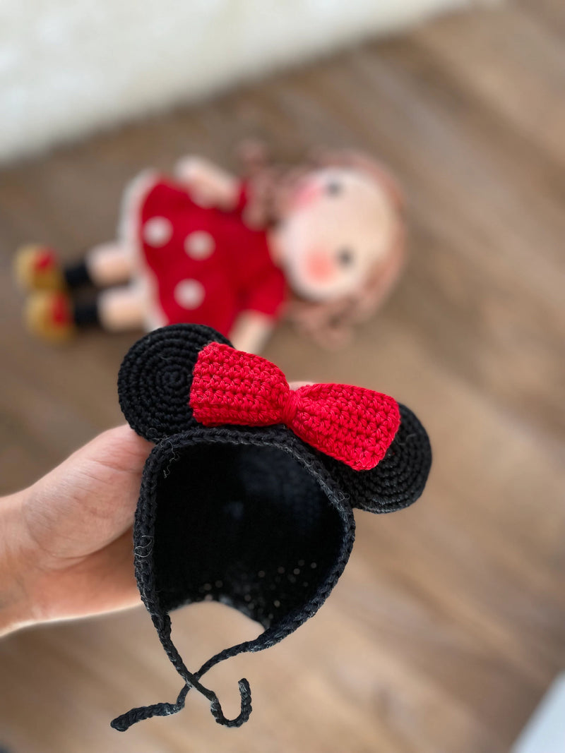 Handmade crochet Micky Girl Doll with a red dress, black ears, and a red bow. This amigurumi doll is customizable with a name on a leather label, perfect for personalized gifts.