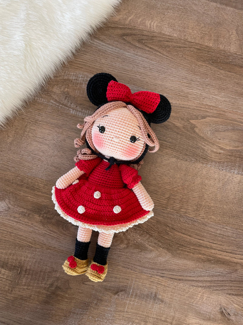 Handmade crochet Micky Girl Doll with a red dress, black ears, and a red bow. This amigurumi doll is customizable with a name on a leather label, perfect for personalized gifts.