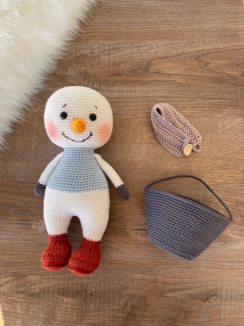 Handmade crocheted snowman toy with red boots, customizable with a name on a leather label, made using amigurumi techniques, perfect as a holiday gift or decor.