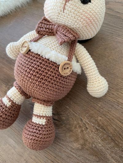 A handmade crocheted Chubby Boy Bunny Rabbit Toy wearing a bow tie and overalls, made with love and care. This amigurumi toy is customizable with a name on a leather label, perfect for nursery decor and personalized baby gifts.