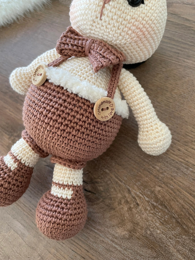 A handmade crocheted Chubby Boy Bunny Rabbit Toy wearing a bow tie and overalls, made with love and care. This amigurumi toy is customizable with a name on a leather label, perfect for nursery decor and personalized baby gifts.