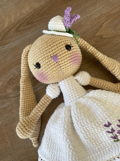 Handmade crocheted Lavender Flower Dressed Bunny Rabbit Toy, complete with a matching hat. This customizable toy includes a name on a leather label and is made using amigurumi techniques. Perfect for nurseries or as a personalized gift.