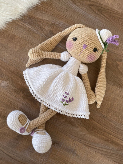 Handmade crocheted Lavender Flower Dressed Bunny Rabbit Toy, complete with a matching hat. This customizable toy includes a name on a leather label and is made using amigurumi techniques. Perfect for nurseries or as a personalized gift.