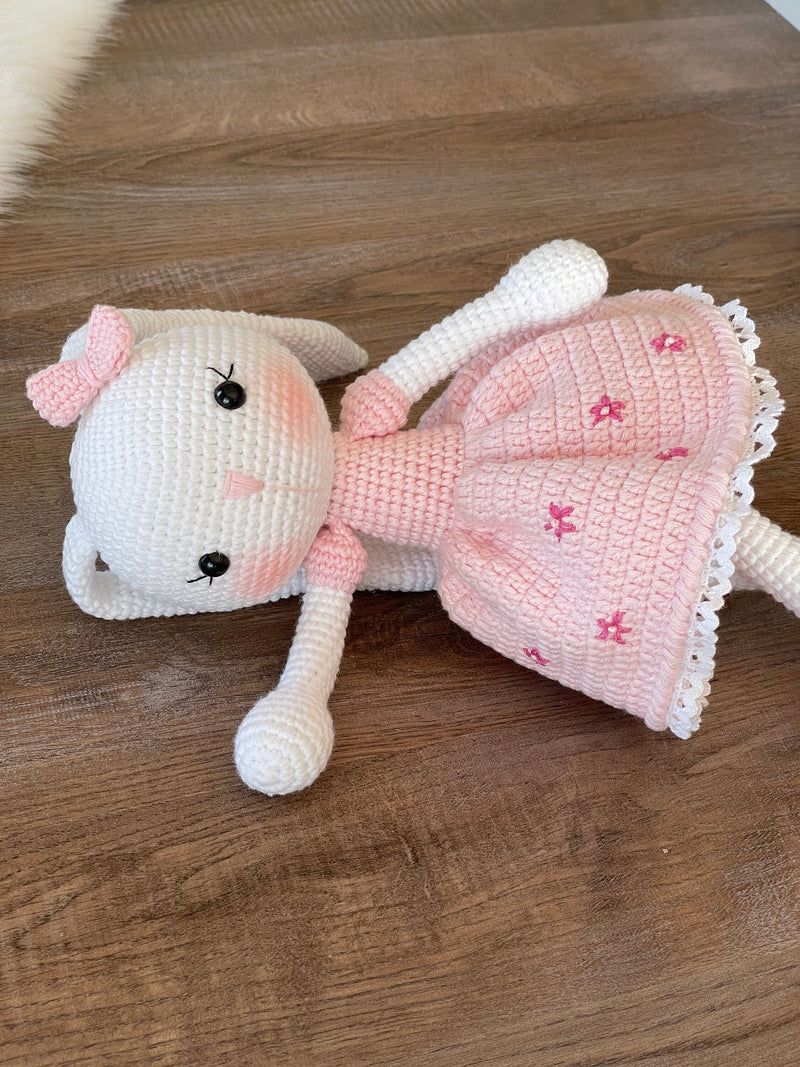 Handmade pink flower bunny rabbit toy crocheted using the amigurumi technique. Features a soft pink dress with floral details and is customizable with a name on a leather label. Perfect baby gift.